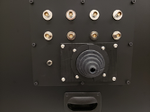 Typical feedthrough interconnect panel that contains low voltage coaxial and triaxial connectors, 3 KV triaxial connectors, a safety interlock and a rubberized boot for direct cable feedthrough